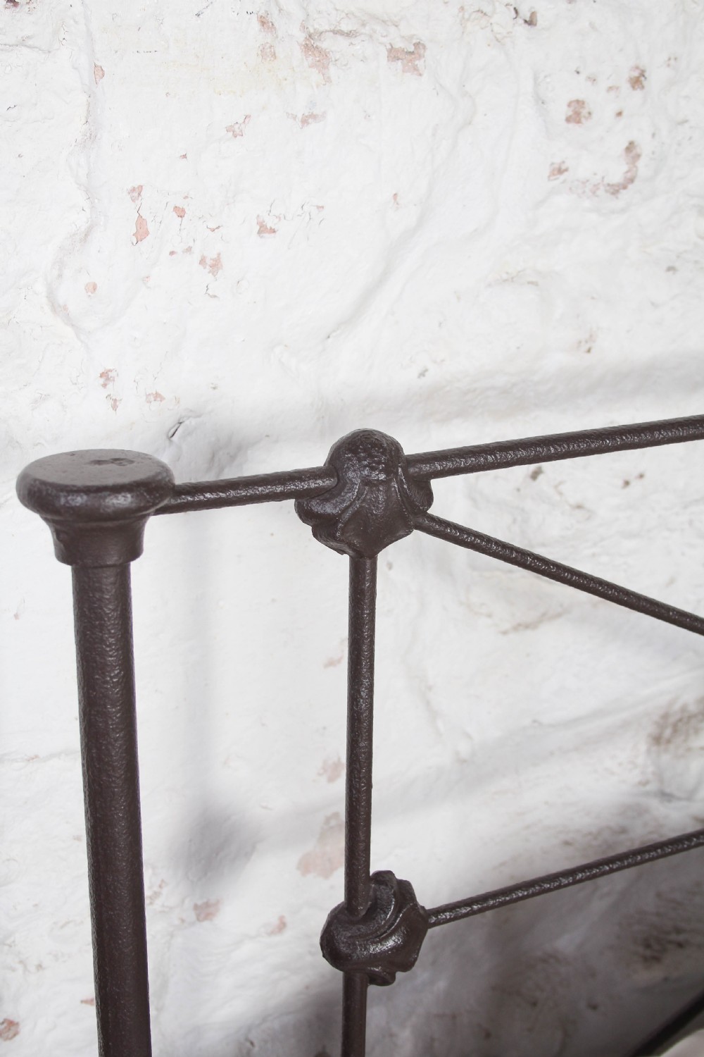 A pair of dark Victorian wrought iron single beds with geometric headboards and footless frames. View VI
