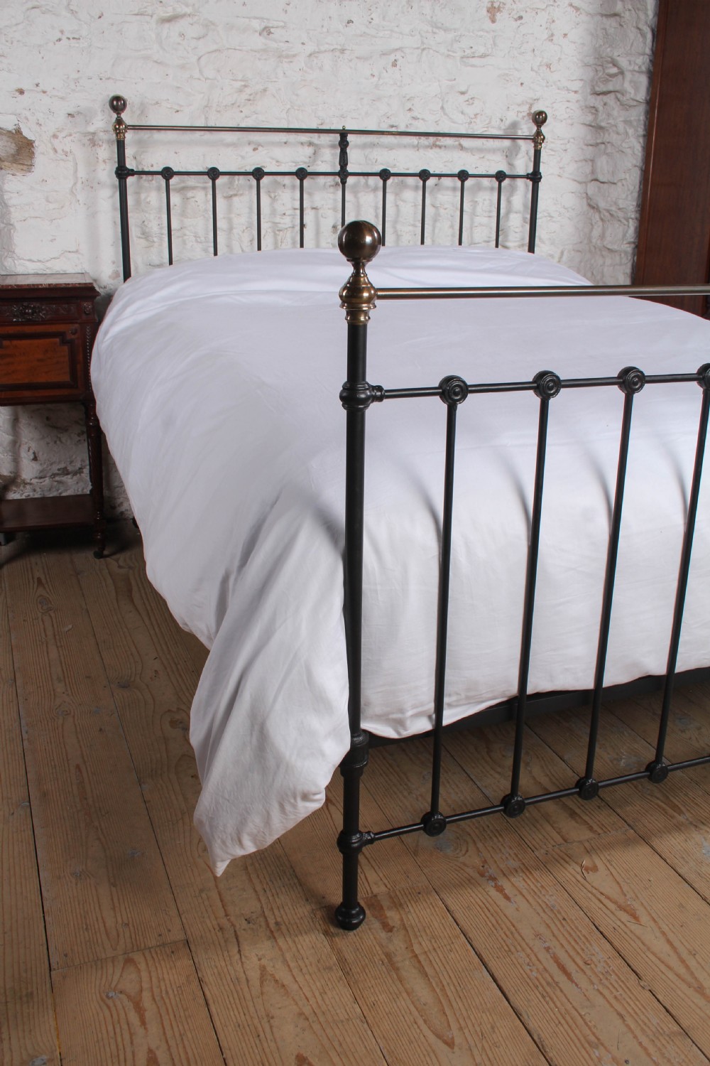 A Victorian black iron bedstead featuring vertical metal spindles, brass top rails, and round brass finials. View IV