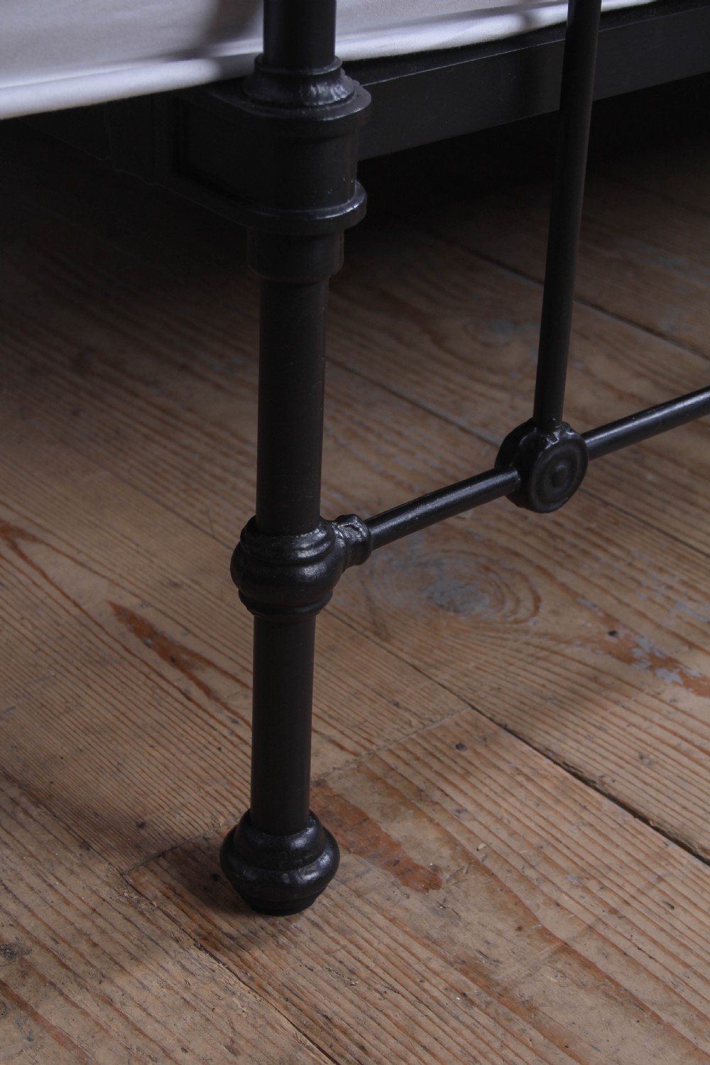 A Victorian black iron bedstead featuring vertical metal spindles, brass top rails, and round brass finials. View VI