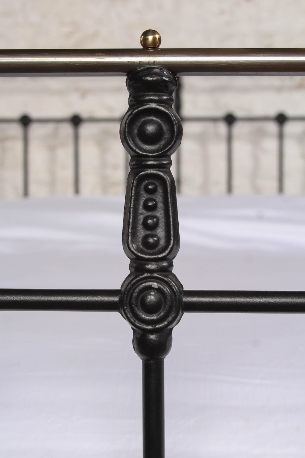 A Victorian black iron bedstead featuring vertical metal spindles, brass top rails, and round brass finials. View VII