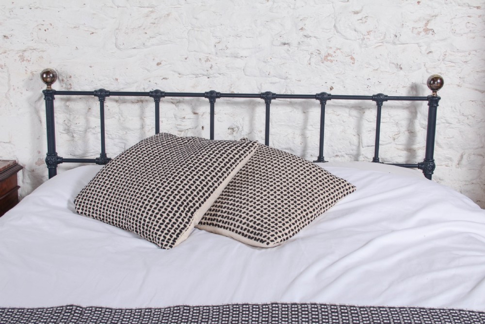 A Victorian style king size dark blue cast iron bedstead featuring decorative brass finials and a low footboard. View III