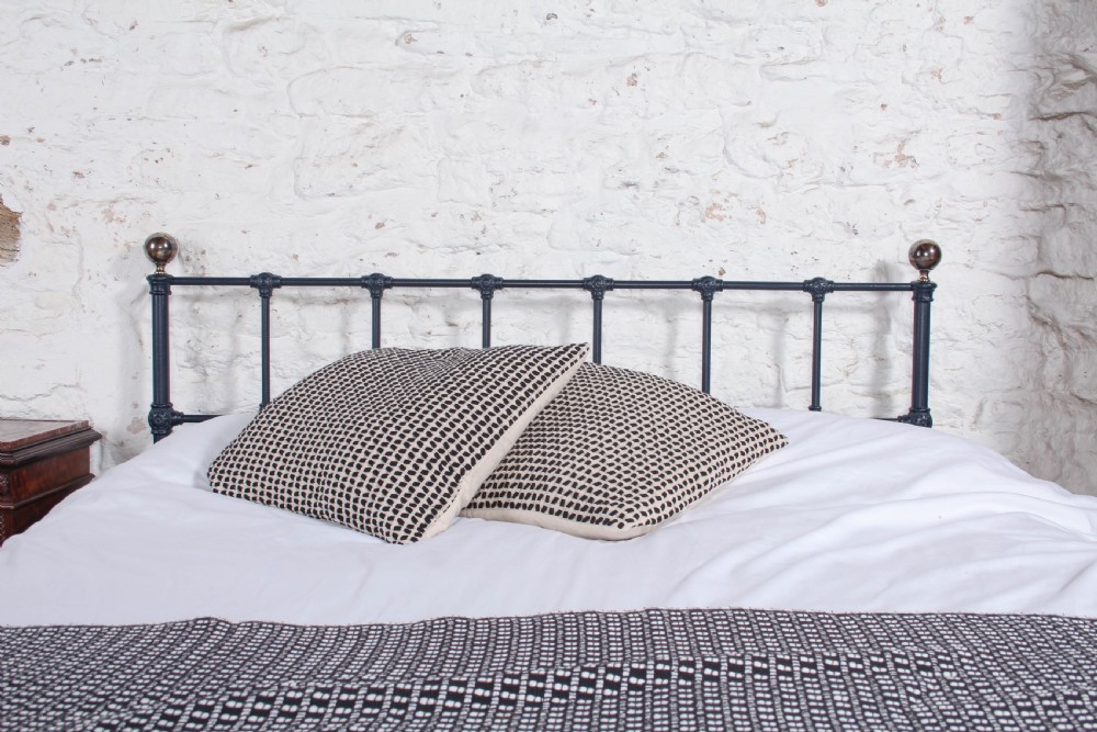 A Victorian style king size dark blue cast iron bedstead featuring decorative brass finials and a low footboard. View VII