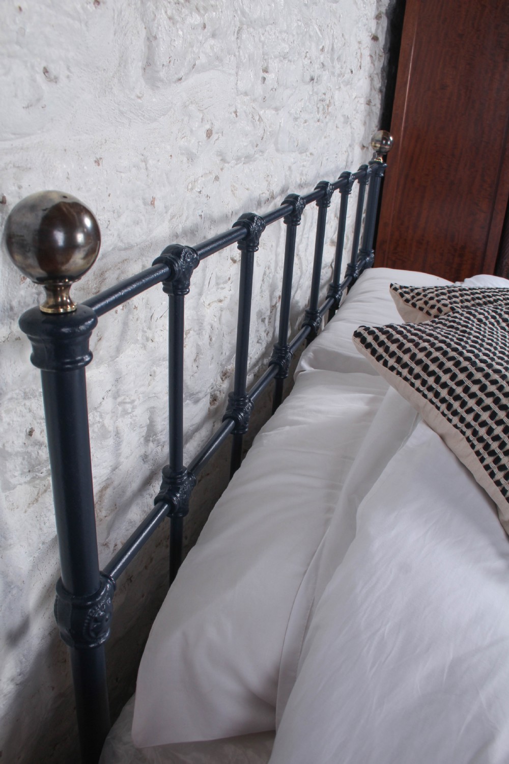 A Victorian style king size dark blue cast iron bedstead featuring decorative brass finials and a low footboard. View VIII