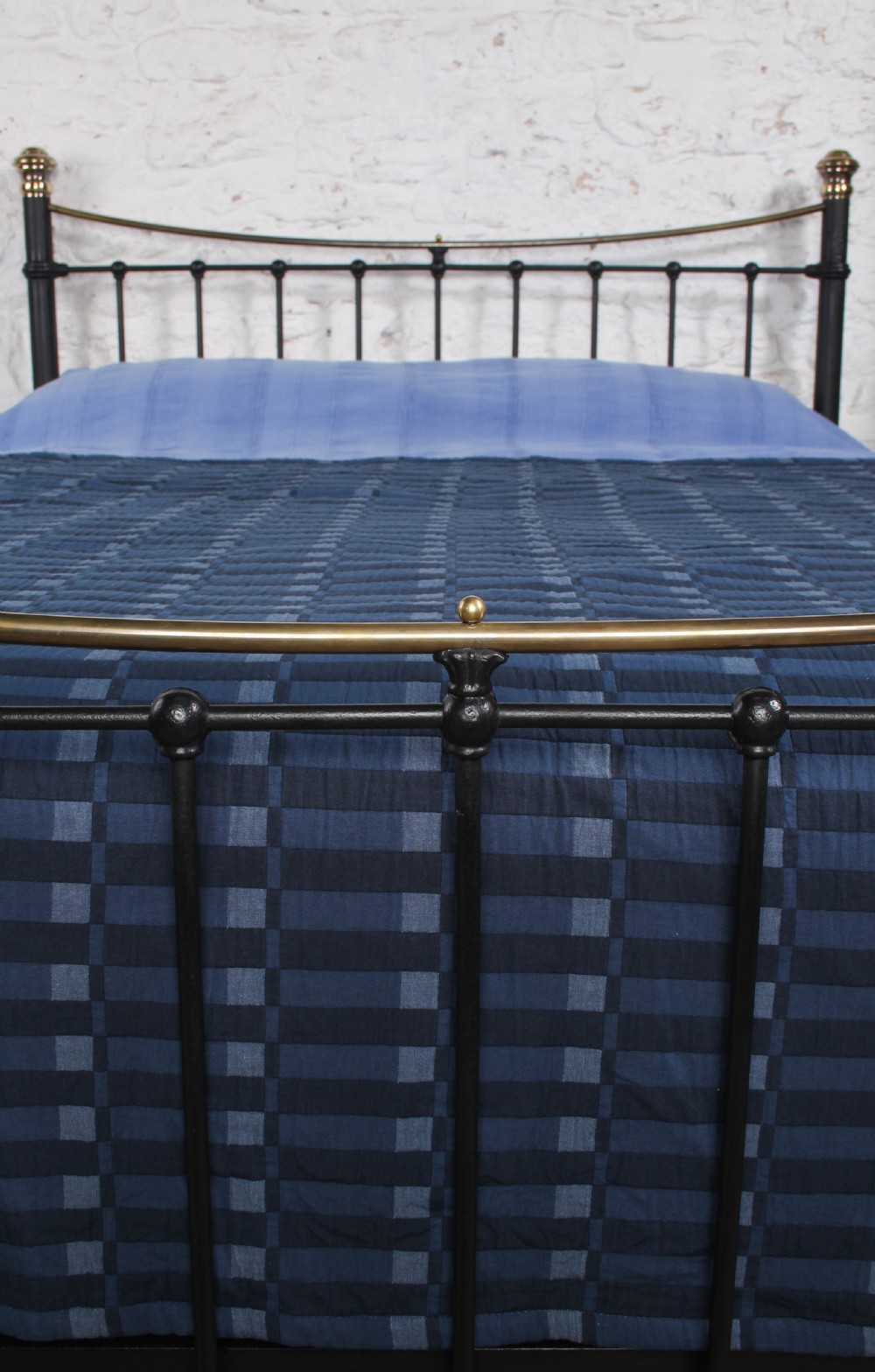 An Edwardian black iron and brass king-size bedstead featuring a curved dip rail and brass corner finials. View IV