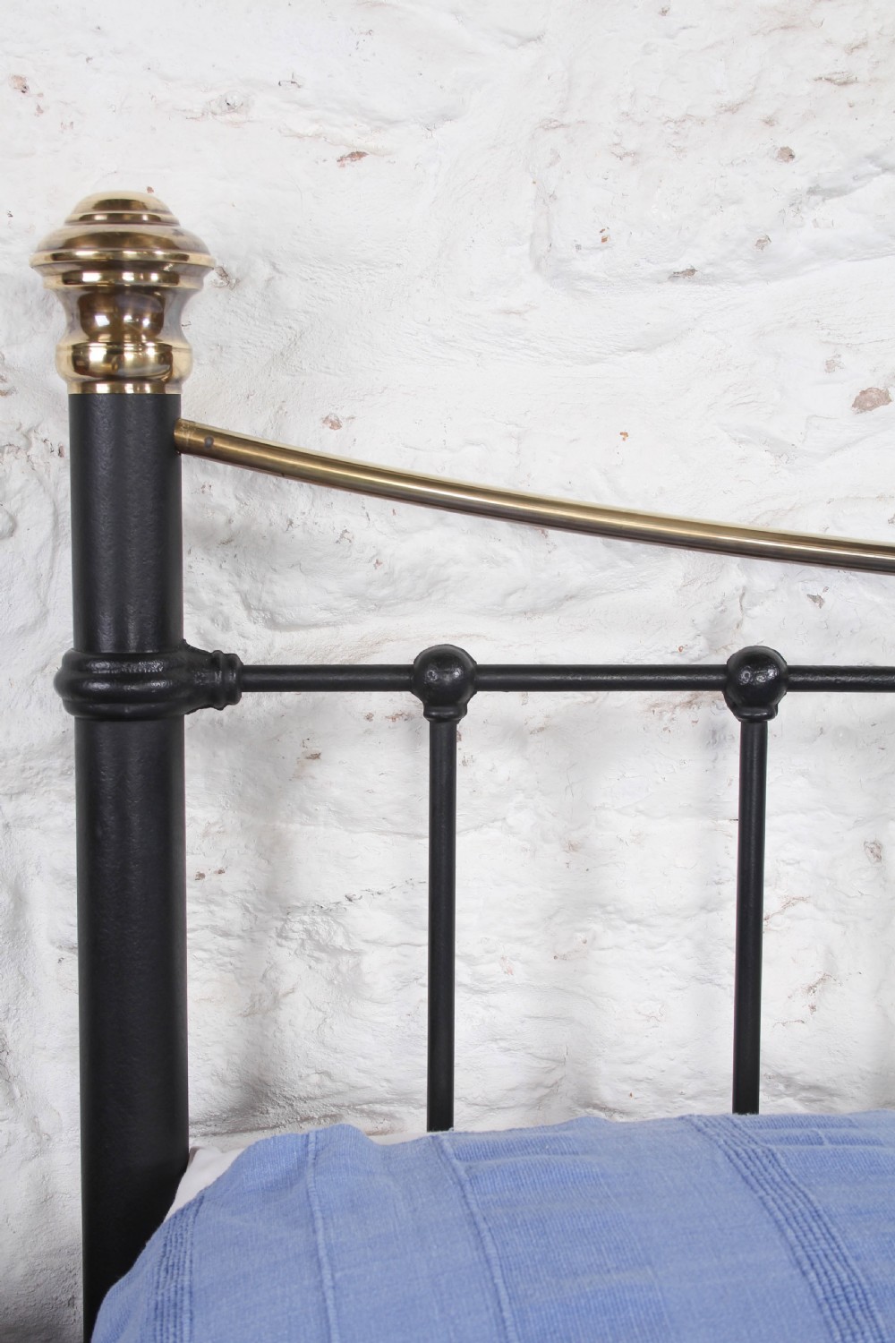 An Edwardian black iron and brass king-size bedstead featuring a curved dip rail and brass corner finials. View IX