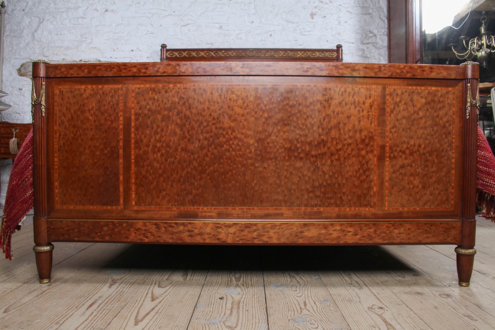 An antique French mahogany king-size bed frame featuring inlaid wood borders, decorative brass mounts, and fluted corner posts. View V
