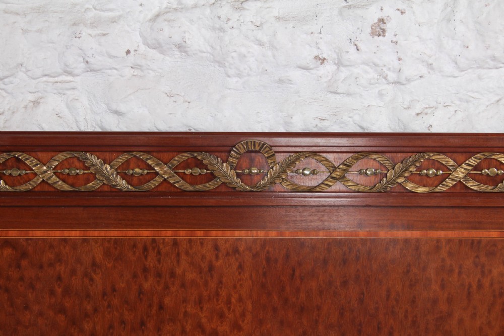 An antique French mahogany king-size bed frame featuring inlaid wood borders, decorative brass mounts, and fluted corner posts. View VII