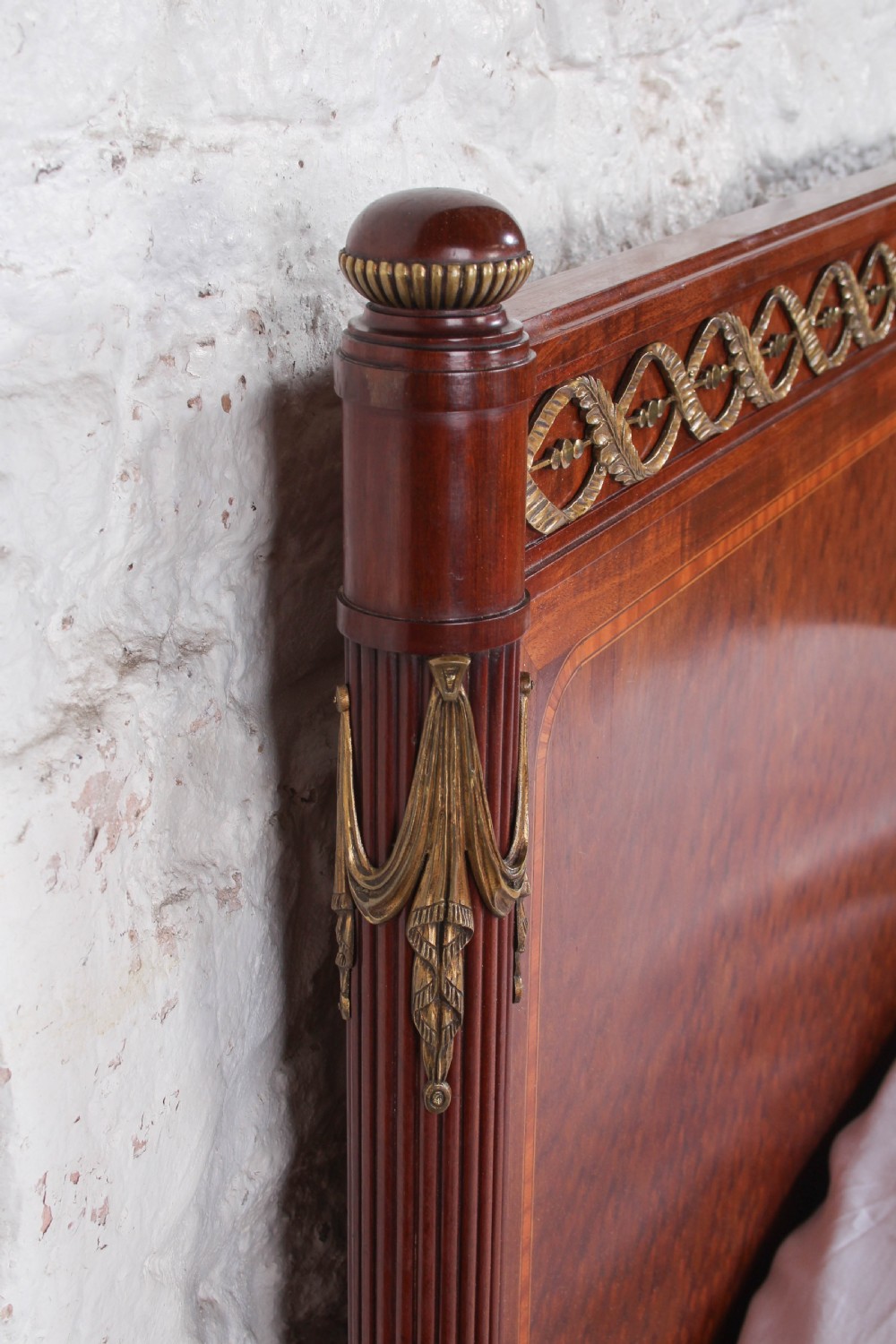 An antique French mahogany king-size bed frame featuring inlaid wood borders, decorative brass mounts, and fluted corner posts. View VIII