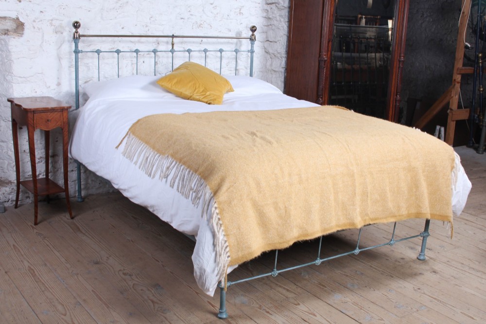 A Victorian king-size light blue painted iron bedstead featuring a straight brass top rail with polished brass corner finials.
