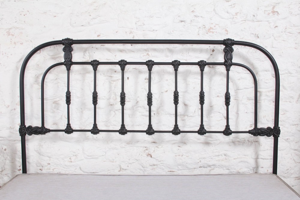 A Victorian Art Nouveau style black cast iron king size bed frame featuring vertical spindles and decorative joinery details. View IX