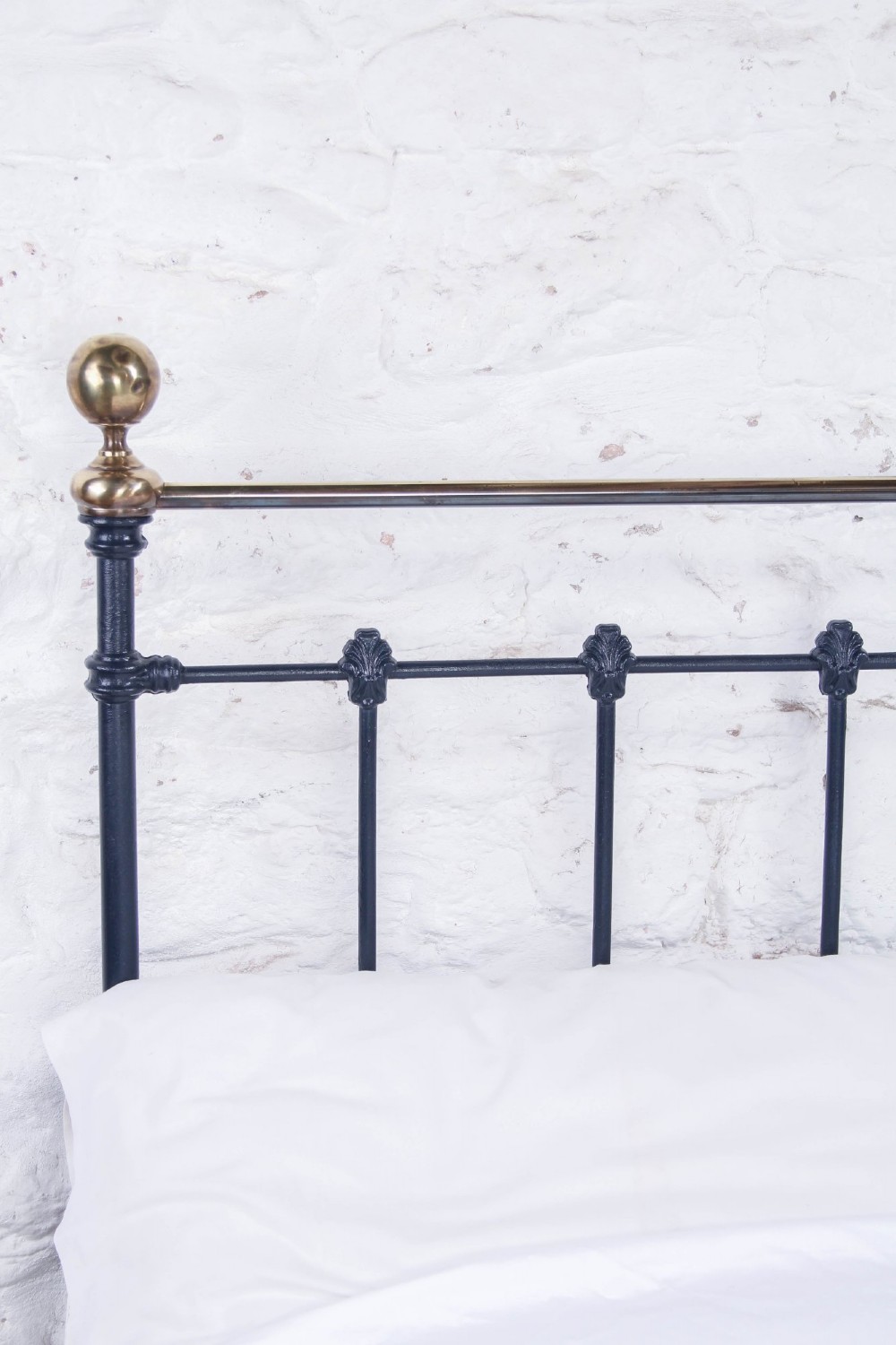 A Victorian double bed frame featuring a dark cast iron headboard with vertical spindles and a polished brass top rail with corner finials. View VI
