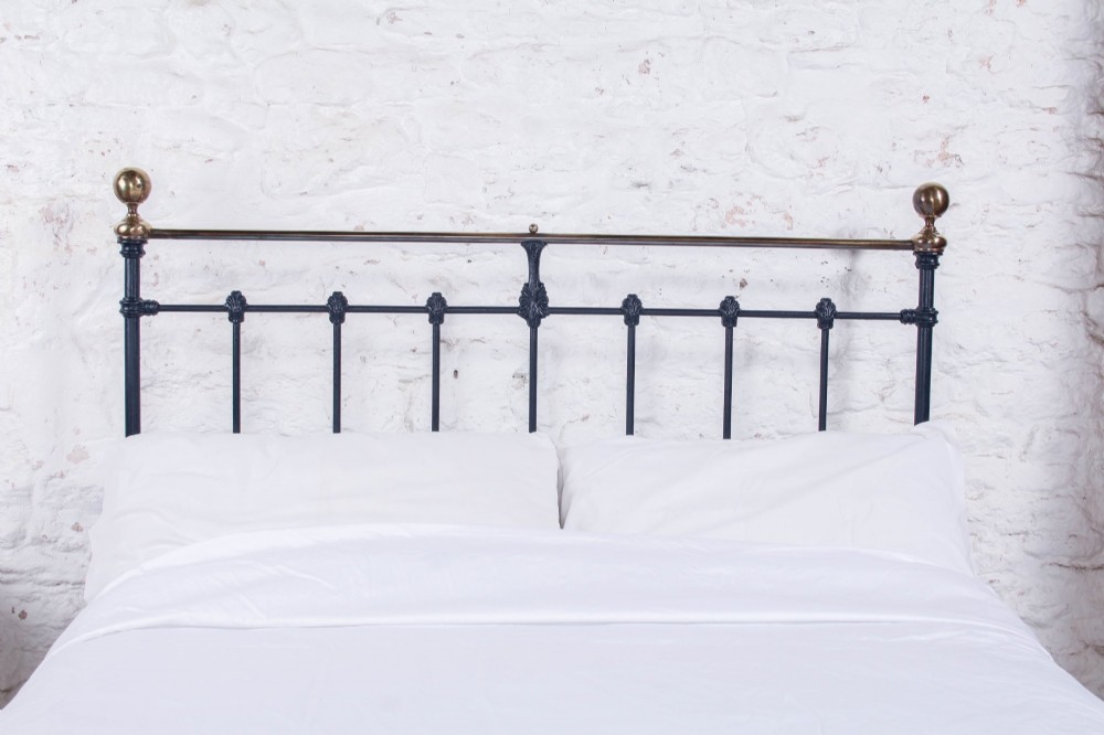 A Victorian double bed frame featuring a dark cast iron headboard with vertical spindles and a polished brass top rail with corner finials. View VII