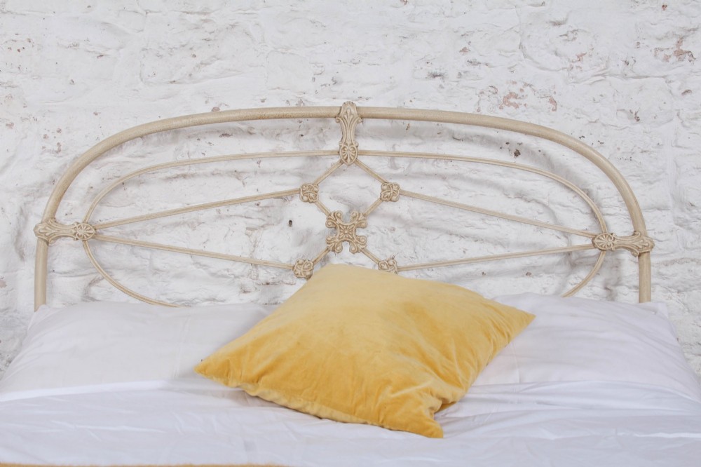 A cream-painted Victorian metal double bed frame featuring a arched wrought iron headboard with decorative cast iron joints. View II