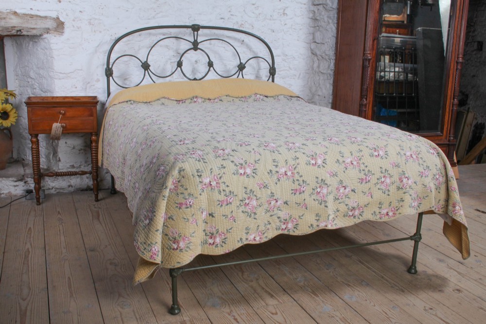 Victorian dark green cast iron double bedstead featuring an arched headboard with decorative scrollwork and a low foot end. View II
