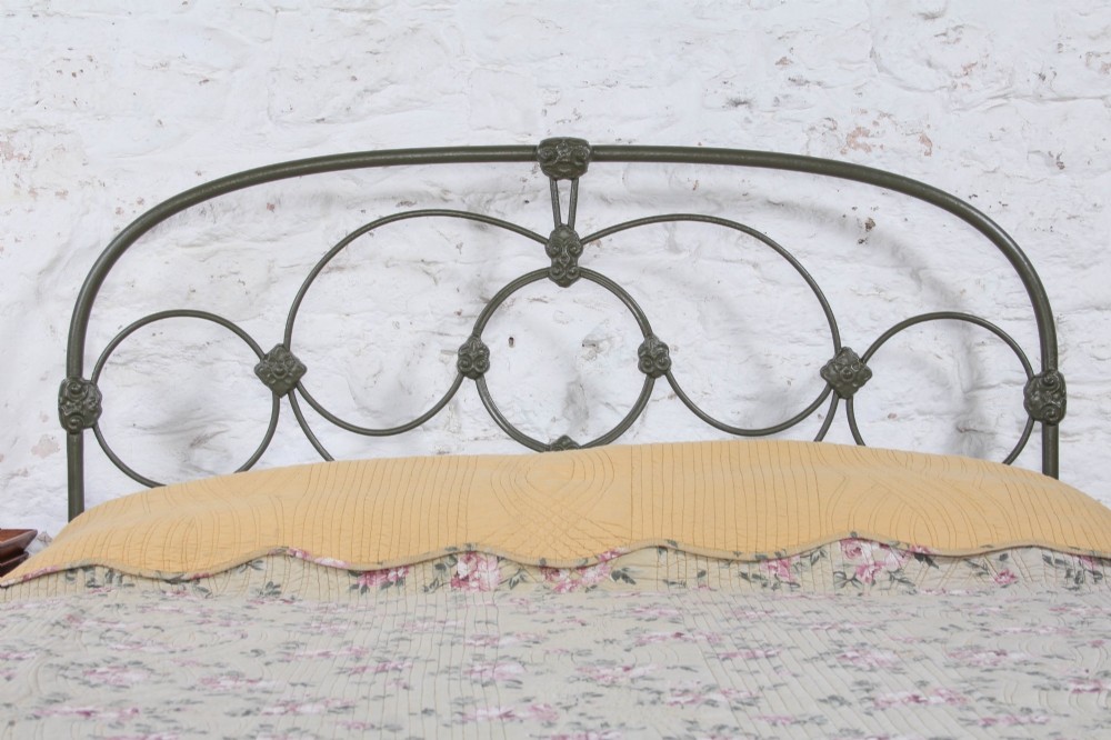 Victorian dark green cast iron double bedstead featuring an arched headboard with decorative scrollwork and a low foot end. View III
