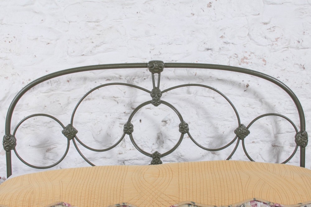Victorian dark green cast iron double bedstead featuring an arched headboard with decorative scrollwork and a low foot end. View VI