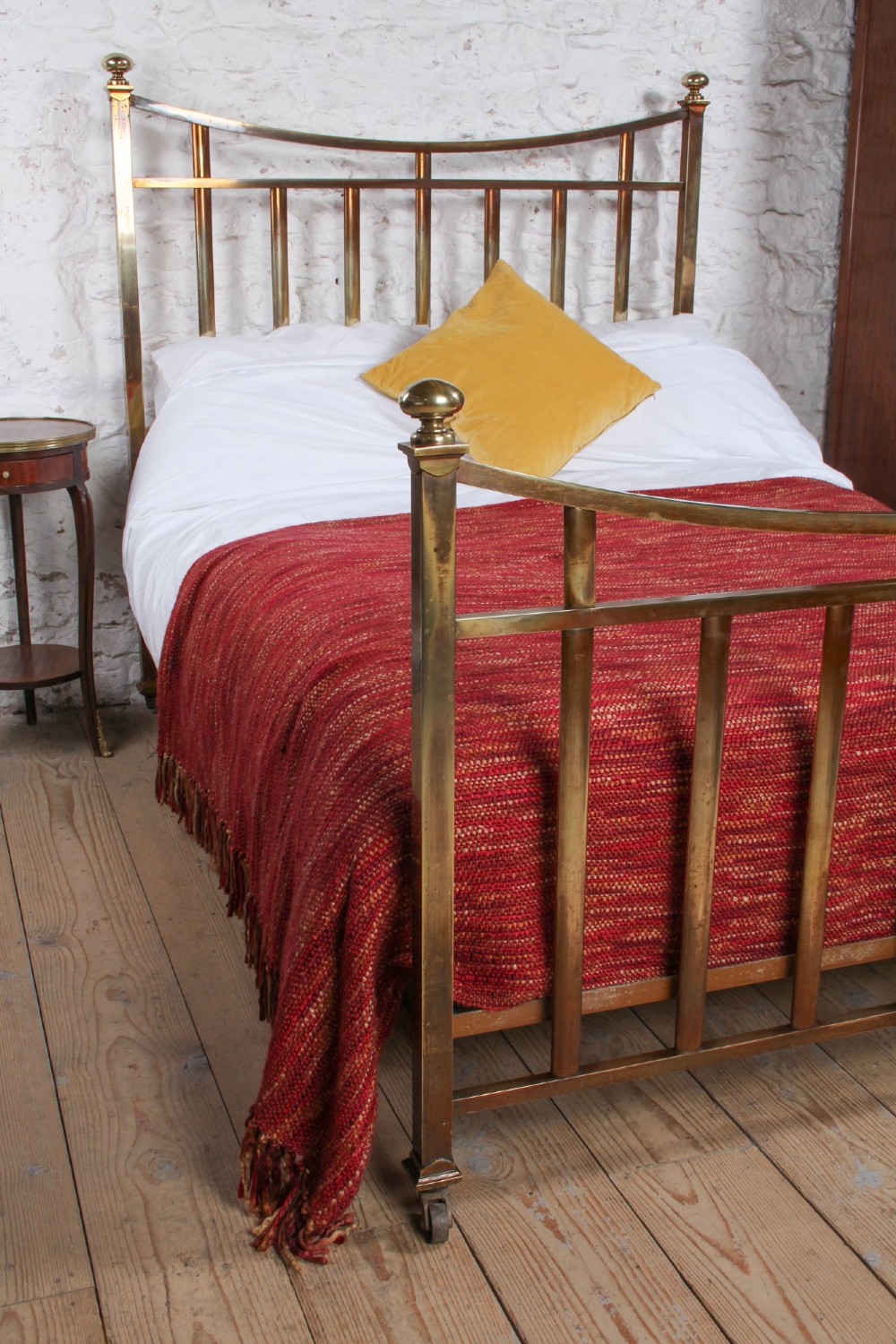 An antique French double bed constructed from brass tubing featuring a curved top rail, vertical spindles, ball finials, and original castors. View II