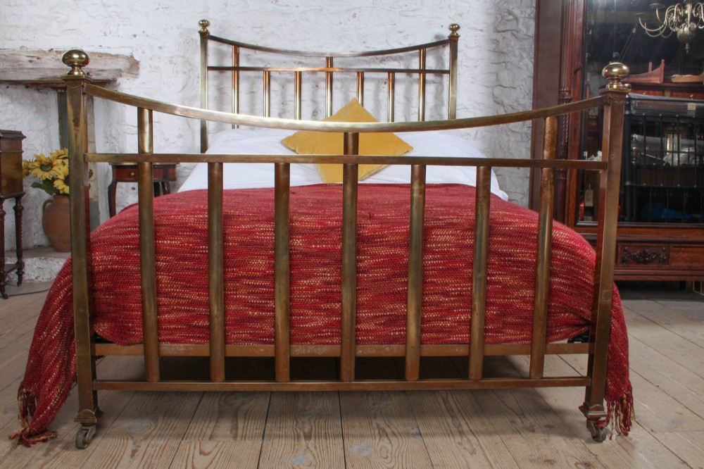 An antique French double bed constructed from brass tubing featuring a curved top rail, vertical spindles, ball finials, and original castors. View III