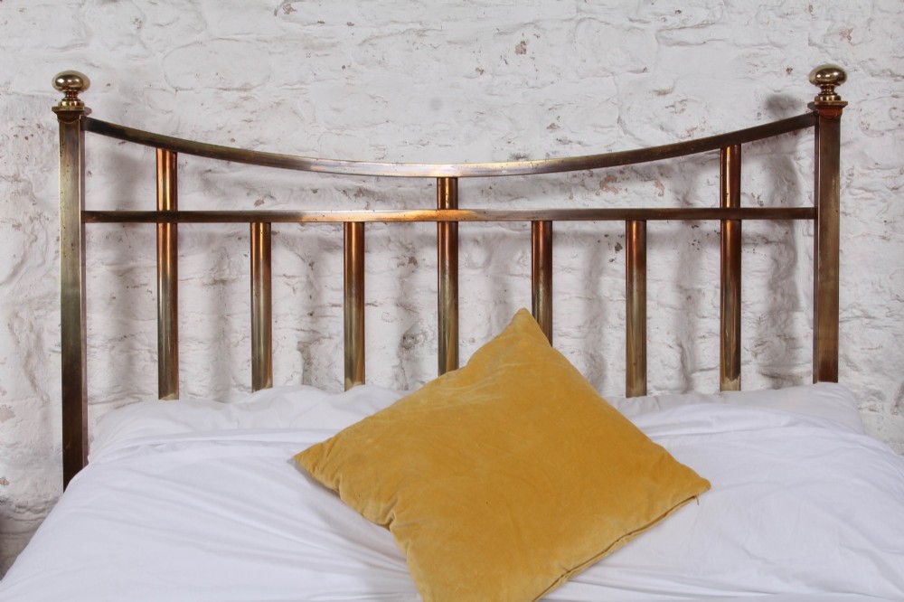 An antique French double bed constructed from brass tubing featuring a curved top rail, vertical spindles, ball finials, and original castors. View V