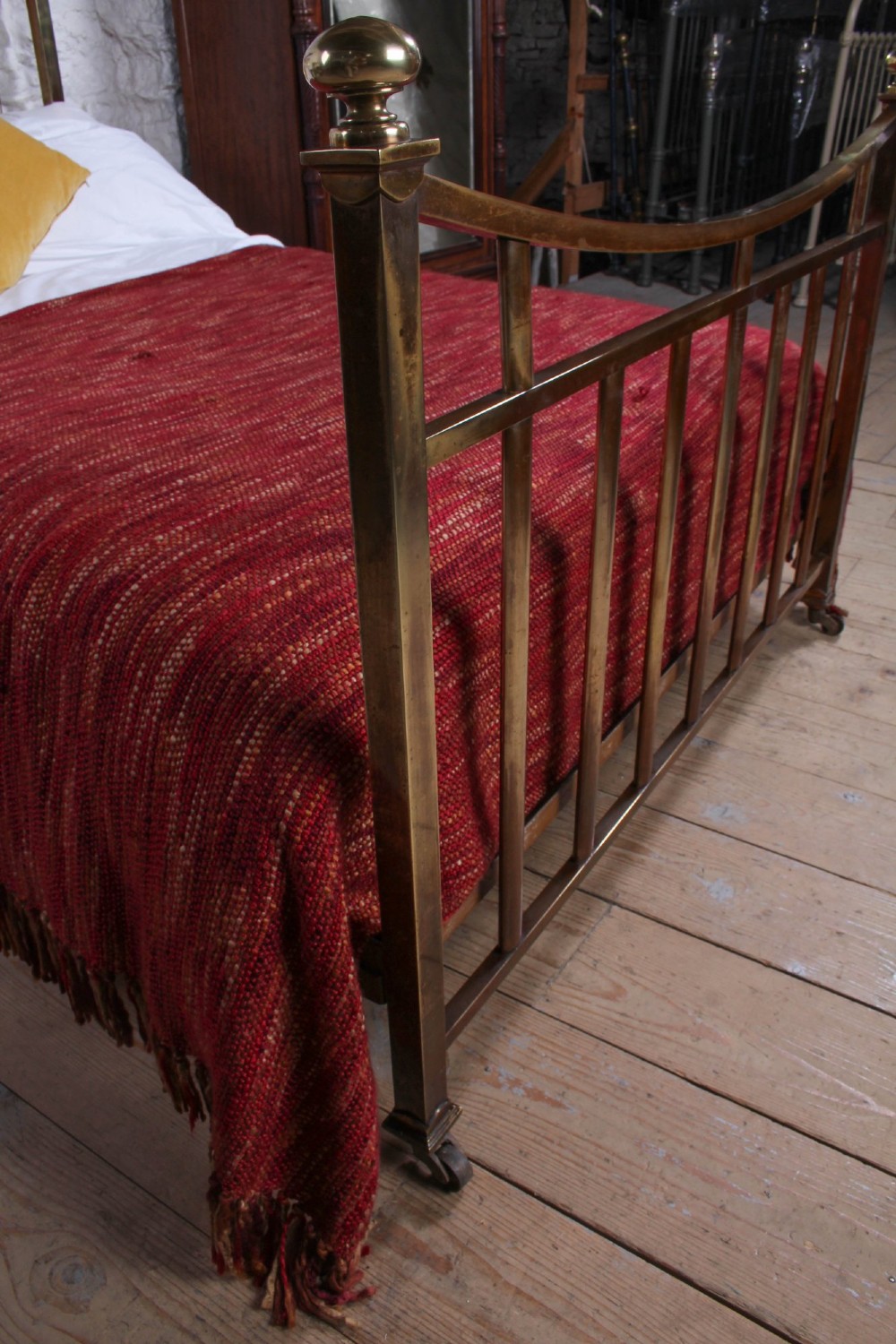 An antique French double bed constructed from brass tubing featuring a curved top rail, vertical spindles, ball finials, and original castors. View VII