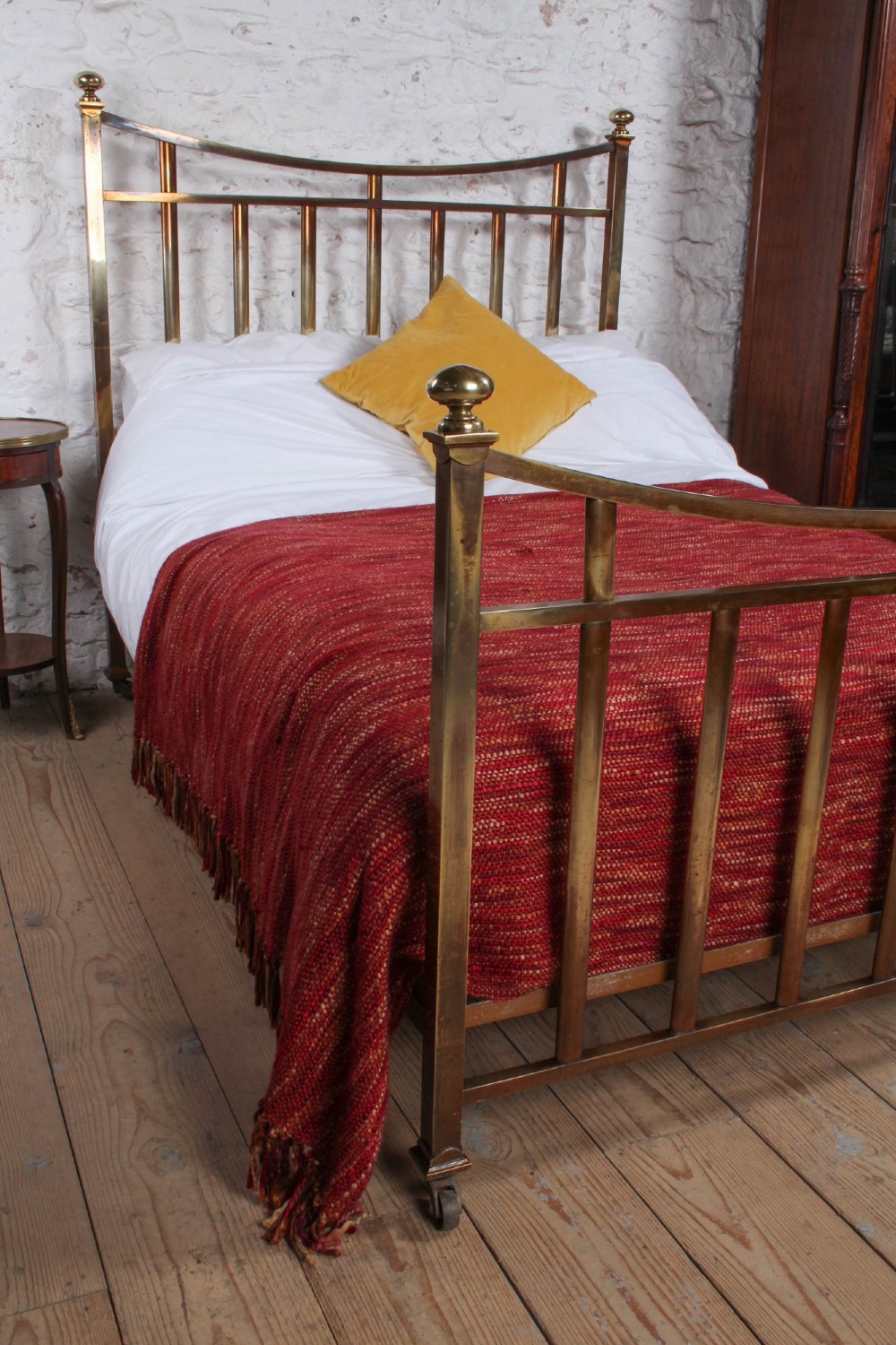 An antique French double bed constructed from brass tubing featuring a curved top rail, vertical spindles, ball finials, and original castors. View VIII