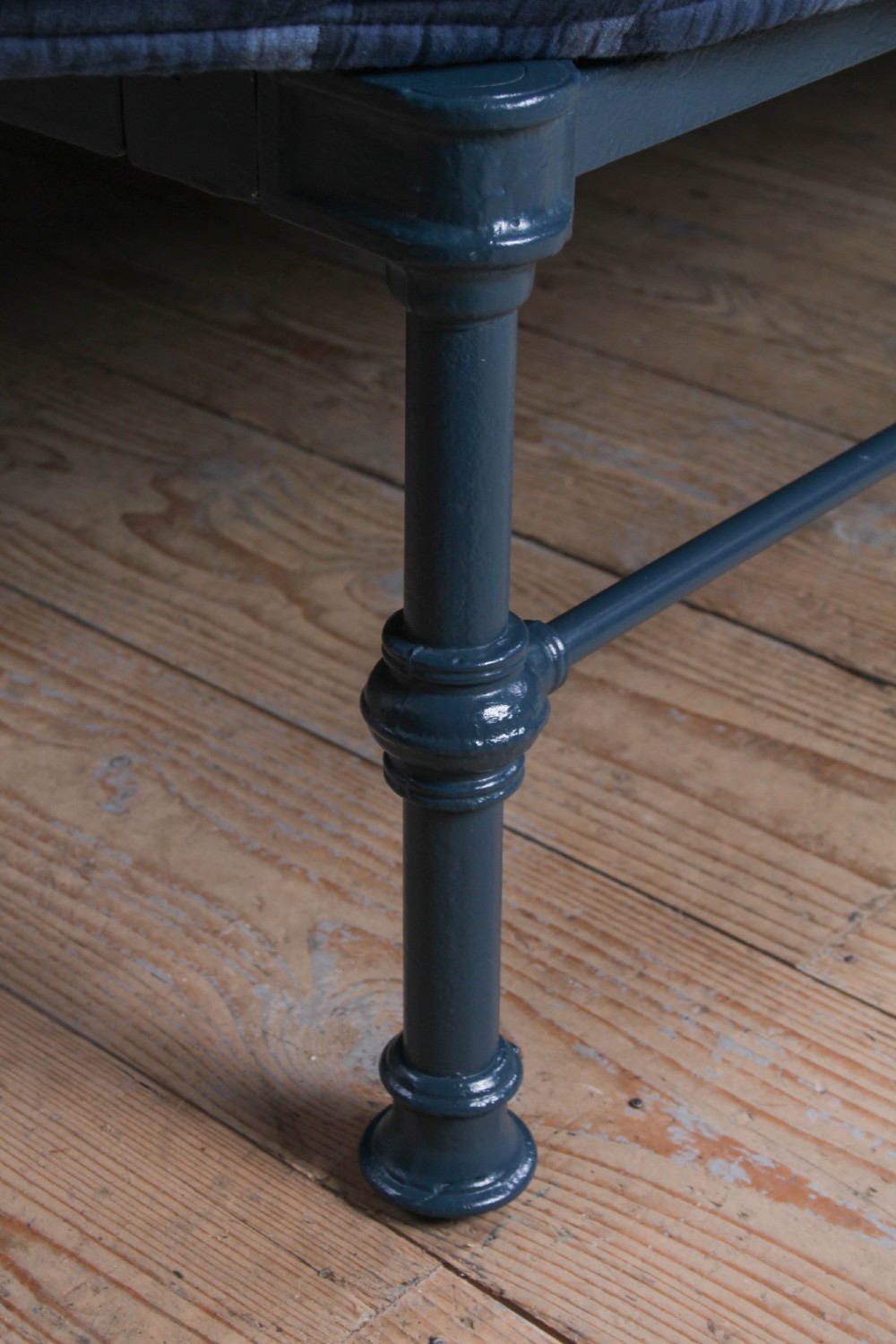 A Victorian king size cast iron bedstead with brass top rail and decorative rosettes, dressed in white and dark blue bedding. View III