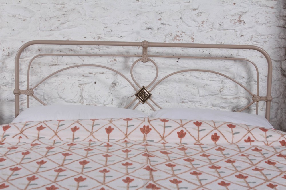 A cream painted wrought iron king size bed frame featuring a high arched headboard with central brass detailing and a low foot end. View II