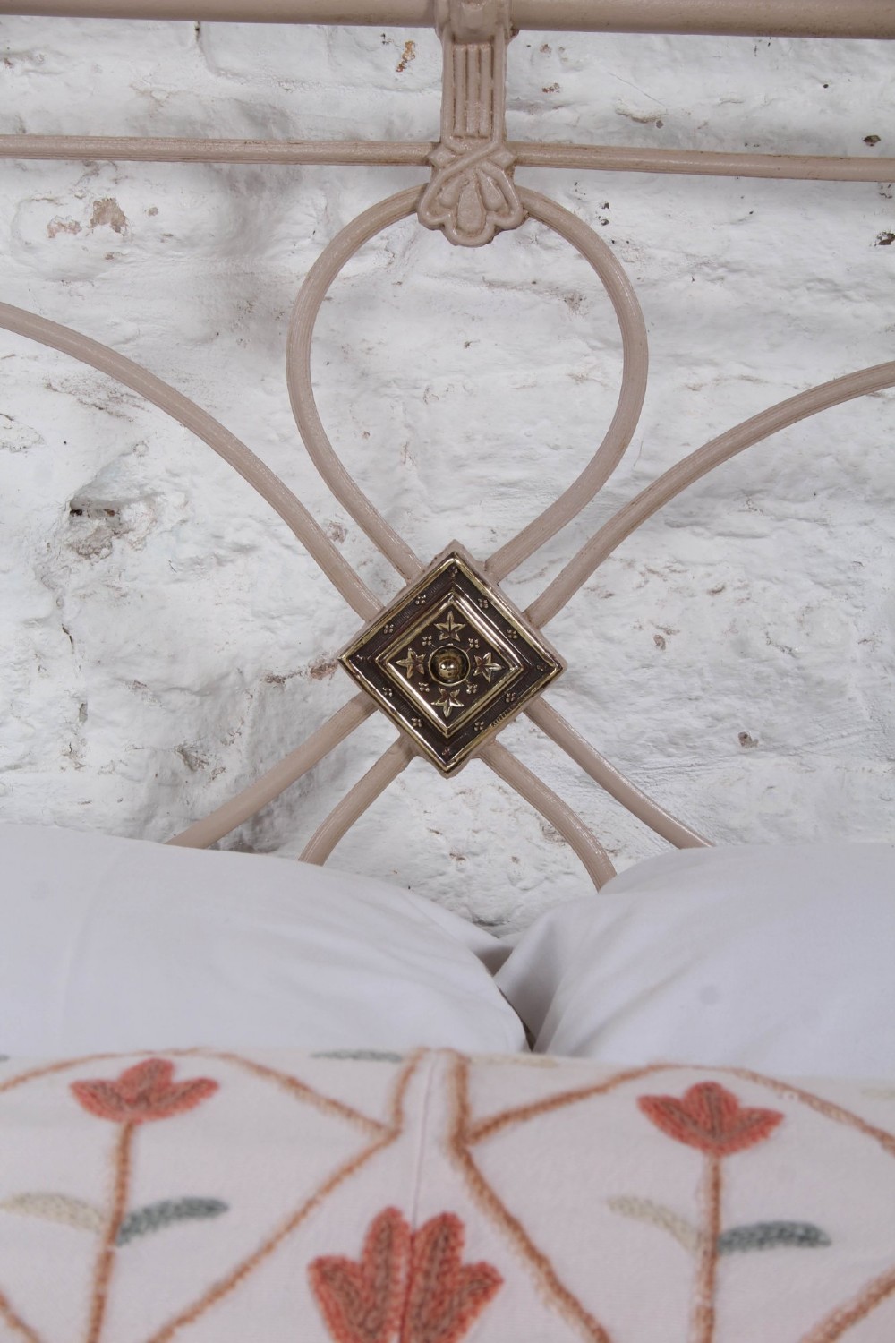 A cream painted wrought iron king size bed frame featuring a high arched headboard with central brass detailing and a low foot end. View V