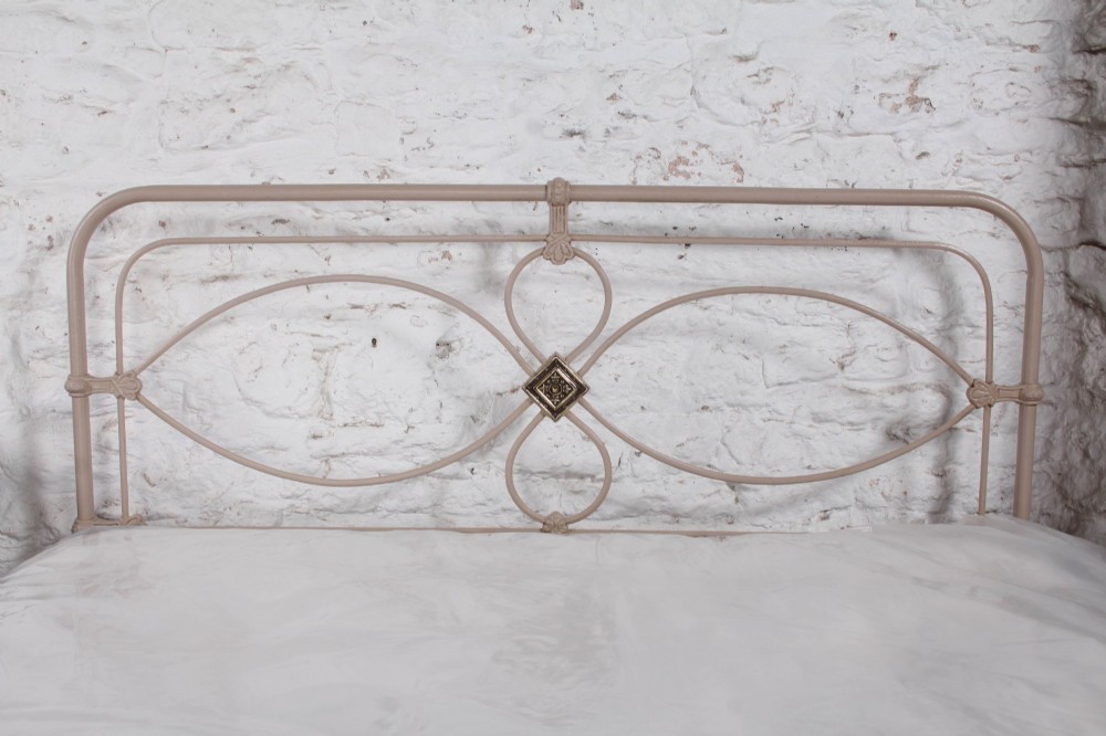 A cream painted wrought iron king size bed frame featuring a high arched headboard with central brass detailing and a low foot end. View VIII