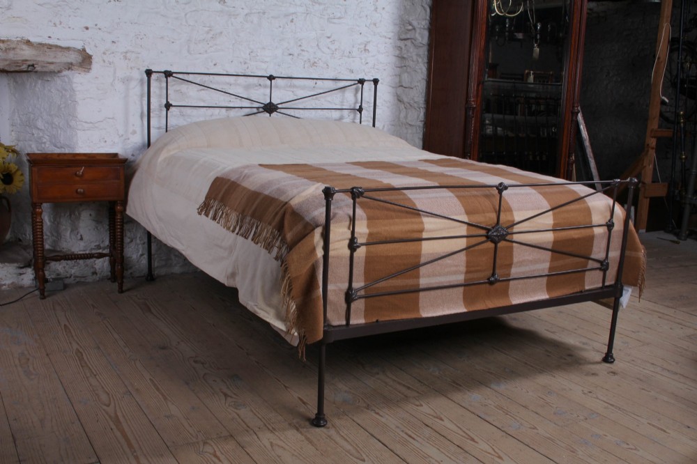 A Victorian dark iron king-size bedstead featuring geometric cross-bracing and cast decorative joints on the headboard and footboard.
