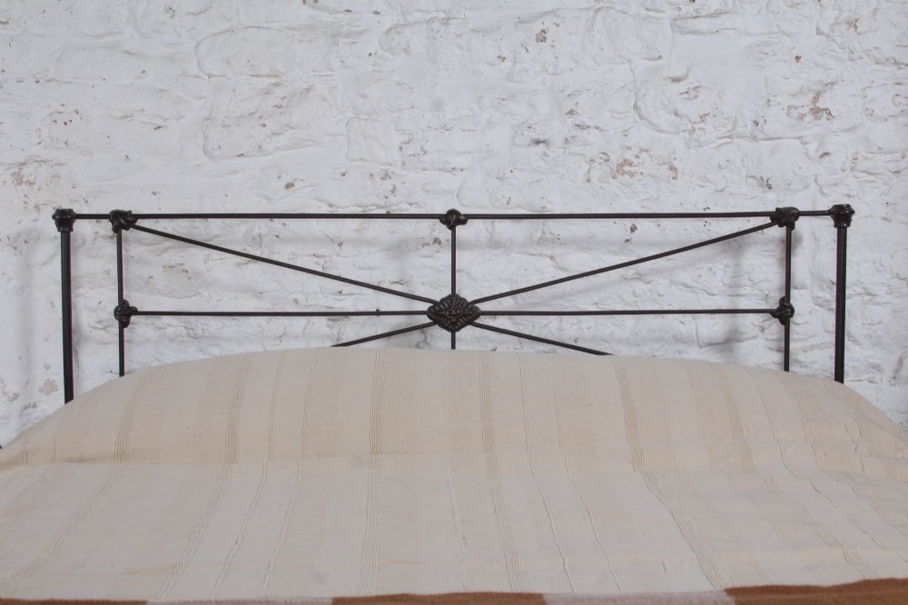 A Victorian dark iron king-size bedstead featuring geometric cross-bracing and cast decorative joints on the headboard and footboard. View II