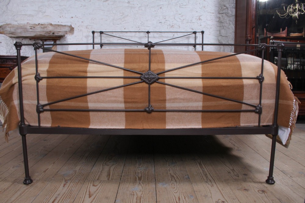 A Victorian dark iron king-size bedstead featuring geometric cross-bracing and cast decorative joints on the headboard and footboard. View III
