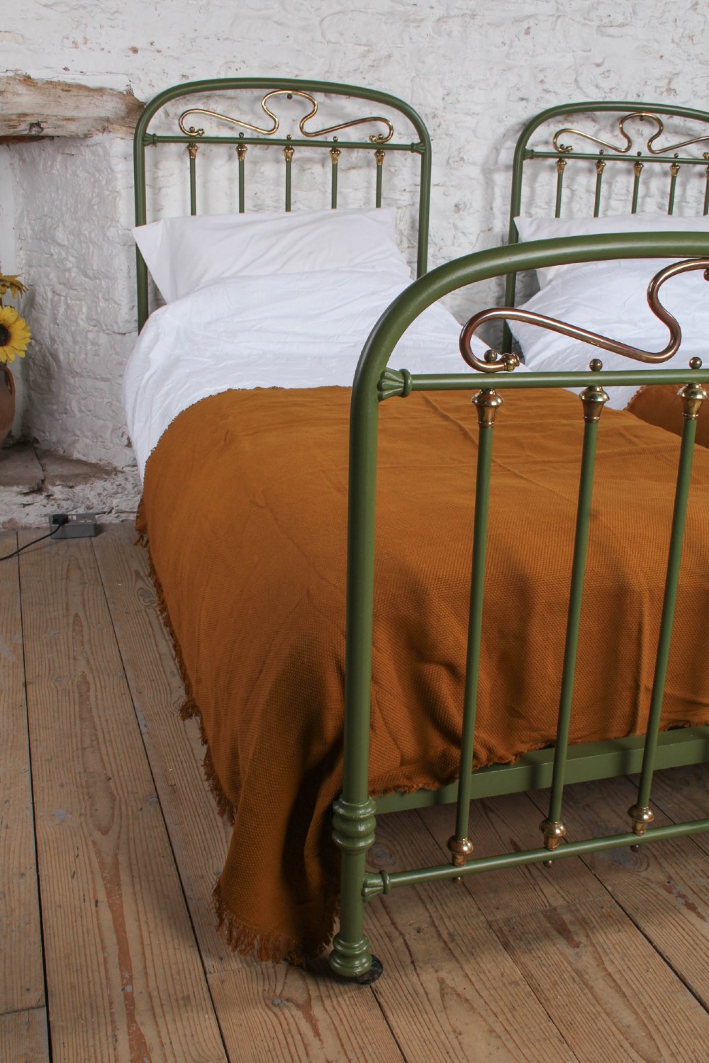 A pair of olive green painted iron single bed frames featuring brass finials, vertical spindles, and decorative scrolled crests. View VII