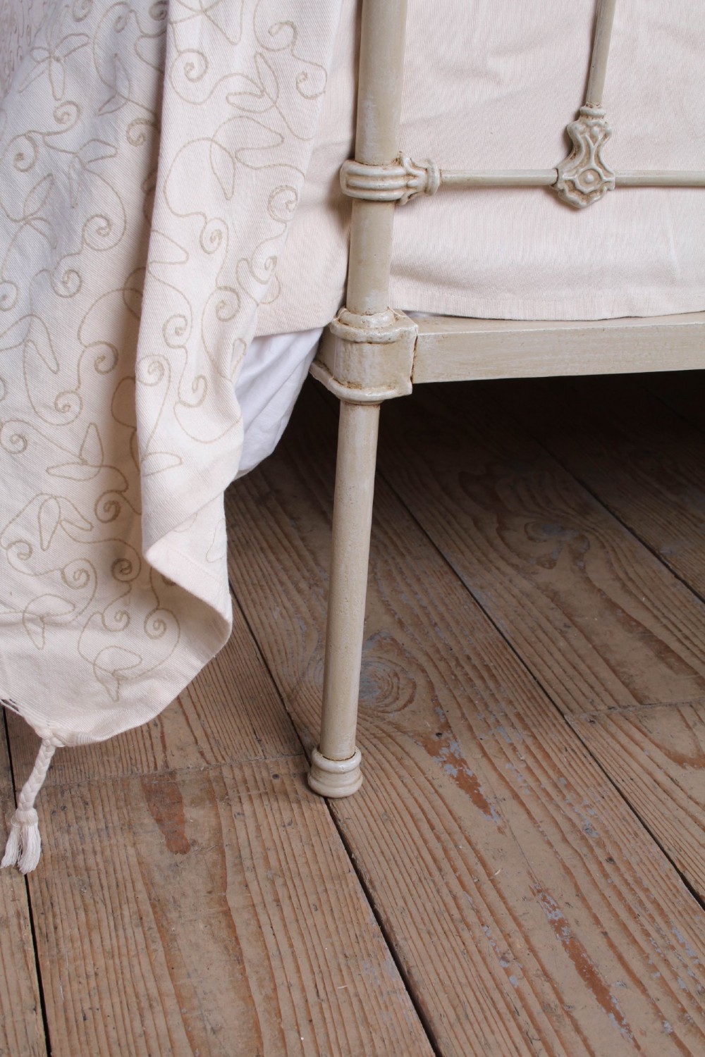 A cream-painted Victorian iron king-size bedstead featuring vertical spindles with cast details and a brass top rail. View VIII