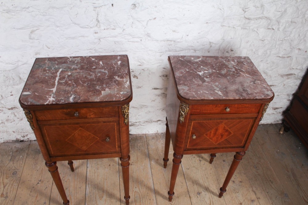 A pair of tall French fruitwood bedside tables featuring square marble tops, diamond parquetry cupboard doors, single drawers, and slender turned tapered legs. View II