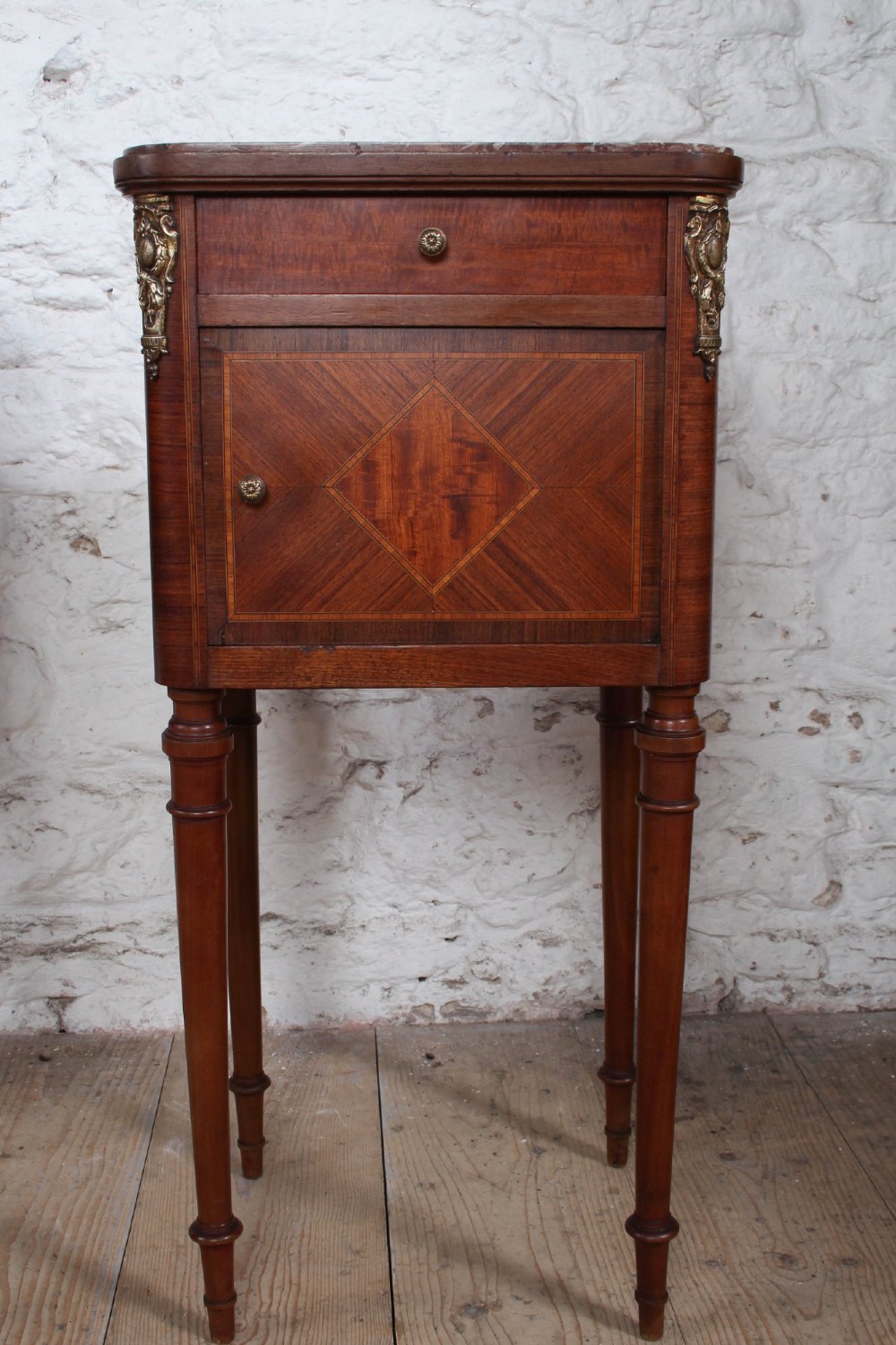A pair of tall French fruitwood bedside tables featuring square marble tops, diamond parquetry cupboard doors, single drawers, and slender turned tapered legs. View V