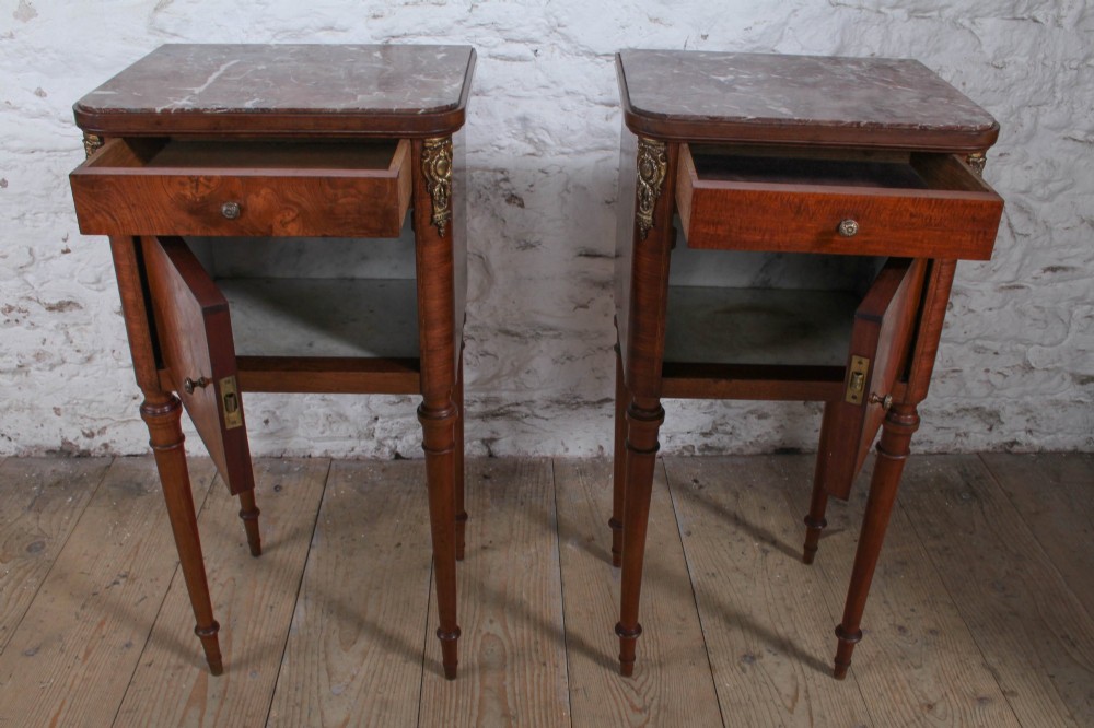 A pair of tall French fruitwood bedside tables featuring square marble tops, diamond parquetry cupboard doors, single drawers, and slender turned tapered legs. View VI