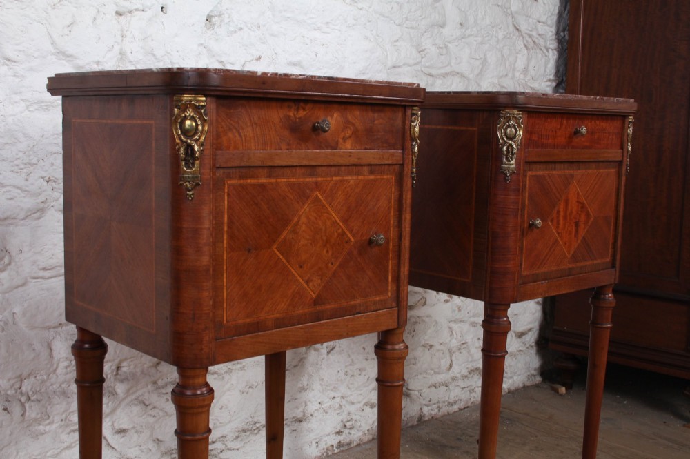 A pair of tall French fruitwood bedside tables featuring square marble tops, diamond parquetry cupboard doors, single drawers, and slender turned tapered legs. View VII