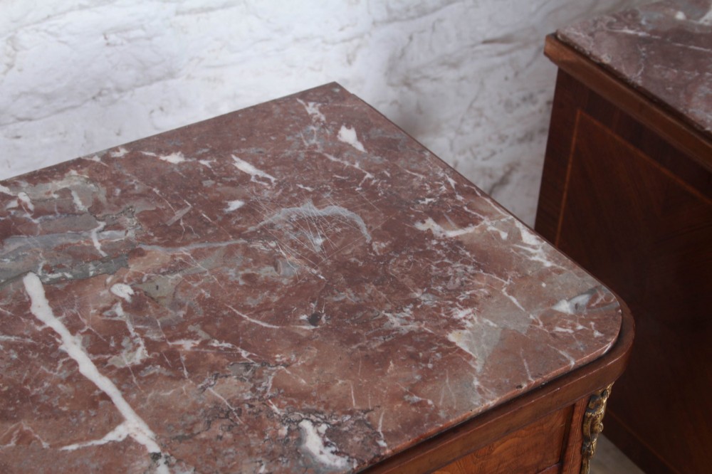 A pair of tall French fruitwood bedside tables featuring square marble tops, diamond parquetry cupboard doors, single drawers, and slender turned tapered legs. View X