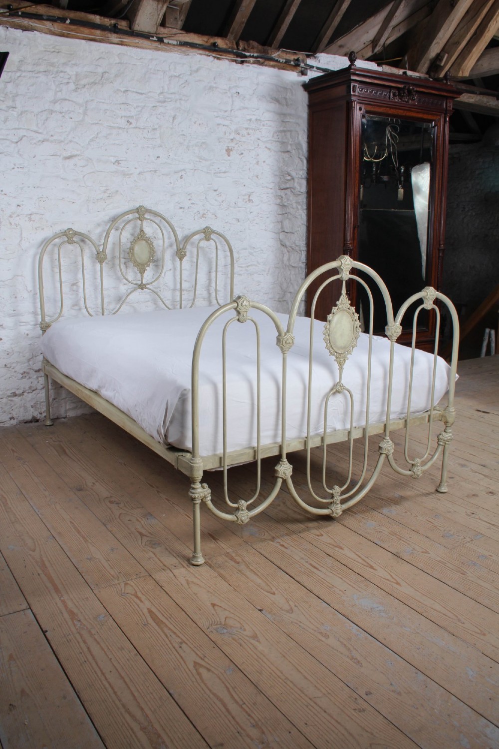 A Victorian cream-painted iron double bed frame featuring a three-hoop headboard and footboard design with central ornate medallions. View VIII