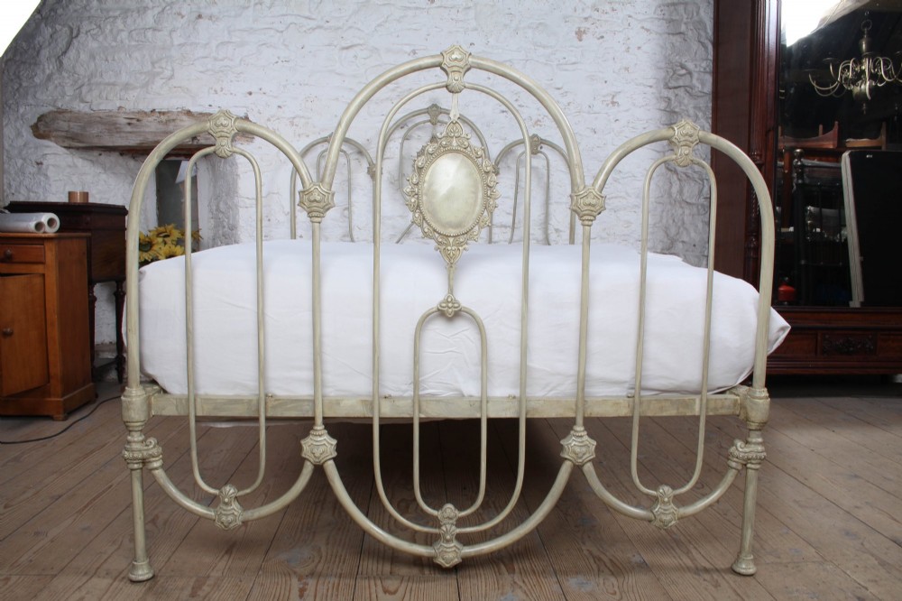 A Victorian cream-painted iron double bed frame featuring a three-hoop headboard and footboard design with central ornate medallions. View X