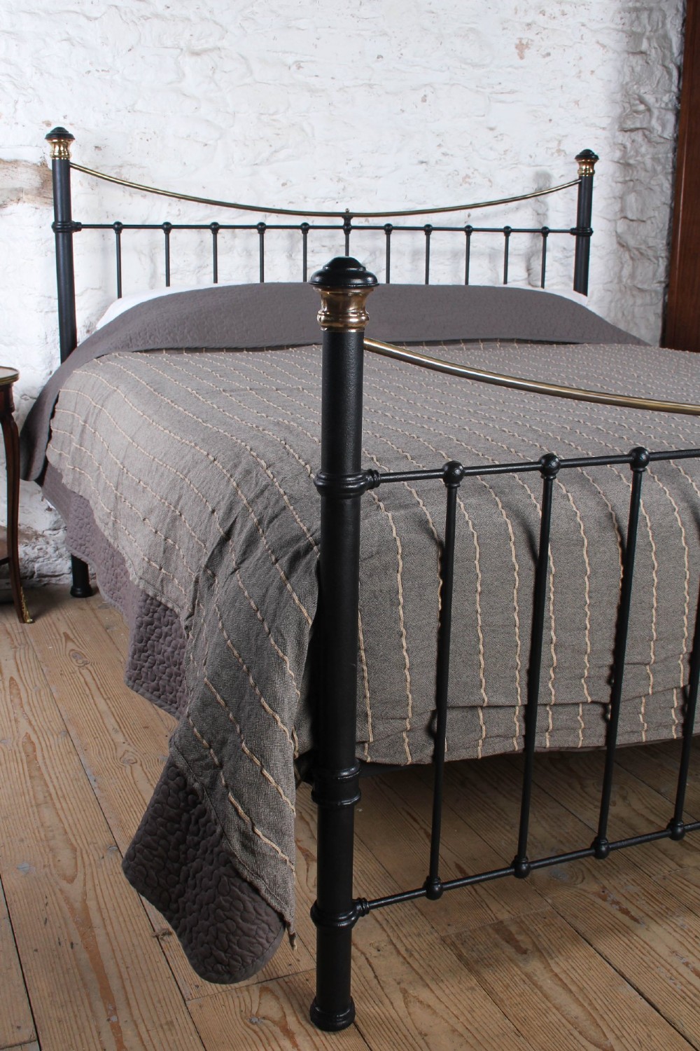 An Edwardian style super king size bed frame made of black painted iron with vertical spindles, topped with curved brass dipping rails and brass finials. View III
