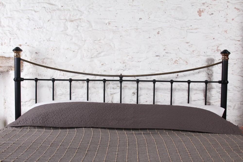 An Edwardian style super king size bed frame made of black painted iron with vertical spindles, topped with curved brass dipping rails and brass finials. View IV