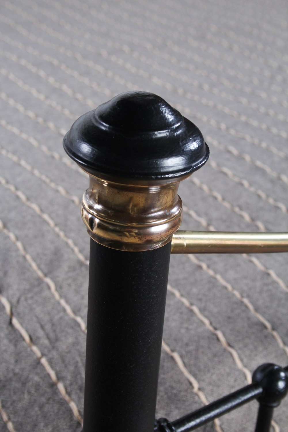 An Edwardian style super king size bed frame made of black painted iron with vertical spindles, topped with curved brass dipping rails and brass finials. View V