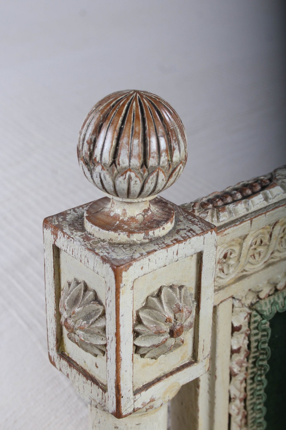 An antique French Louis XVI style bedstead featuring a cream-painted carved wooden frame, fluted posts, finials, and arched headboard and footboard panels upholstered in green velvet. View V