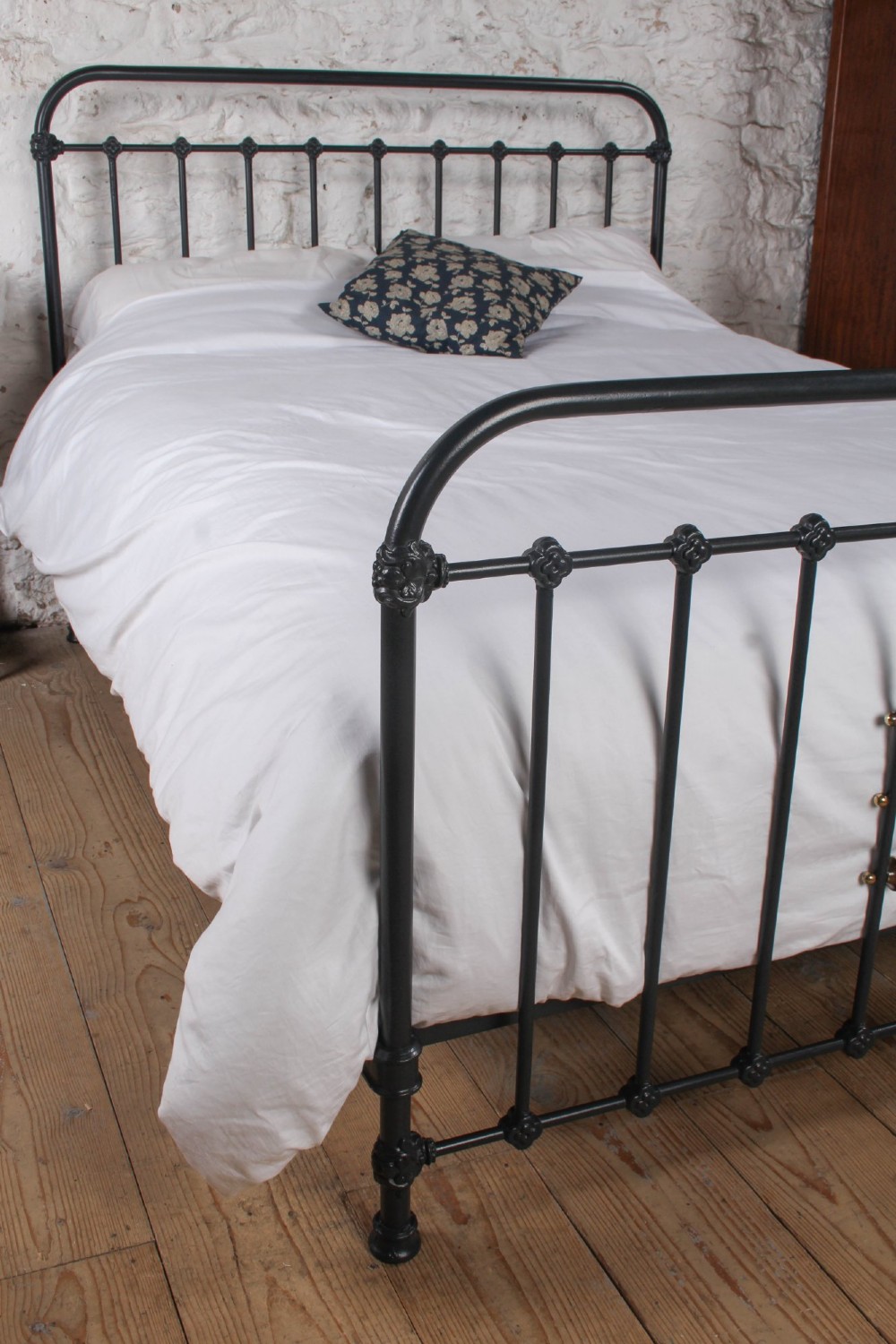 A black iron and brass king-size bed frame featuring vertical spindles and a central brass quatrefoil motif on the footboard. View VI