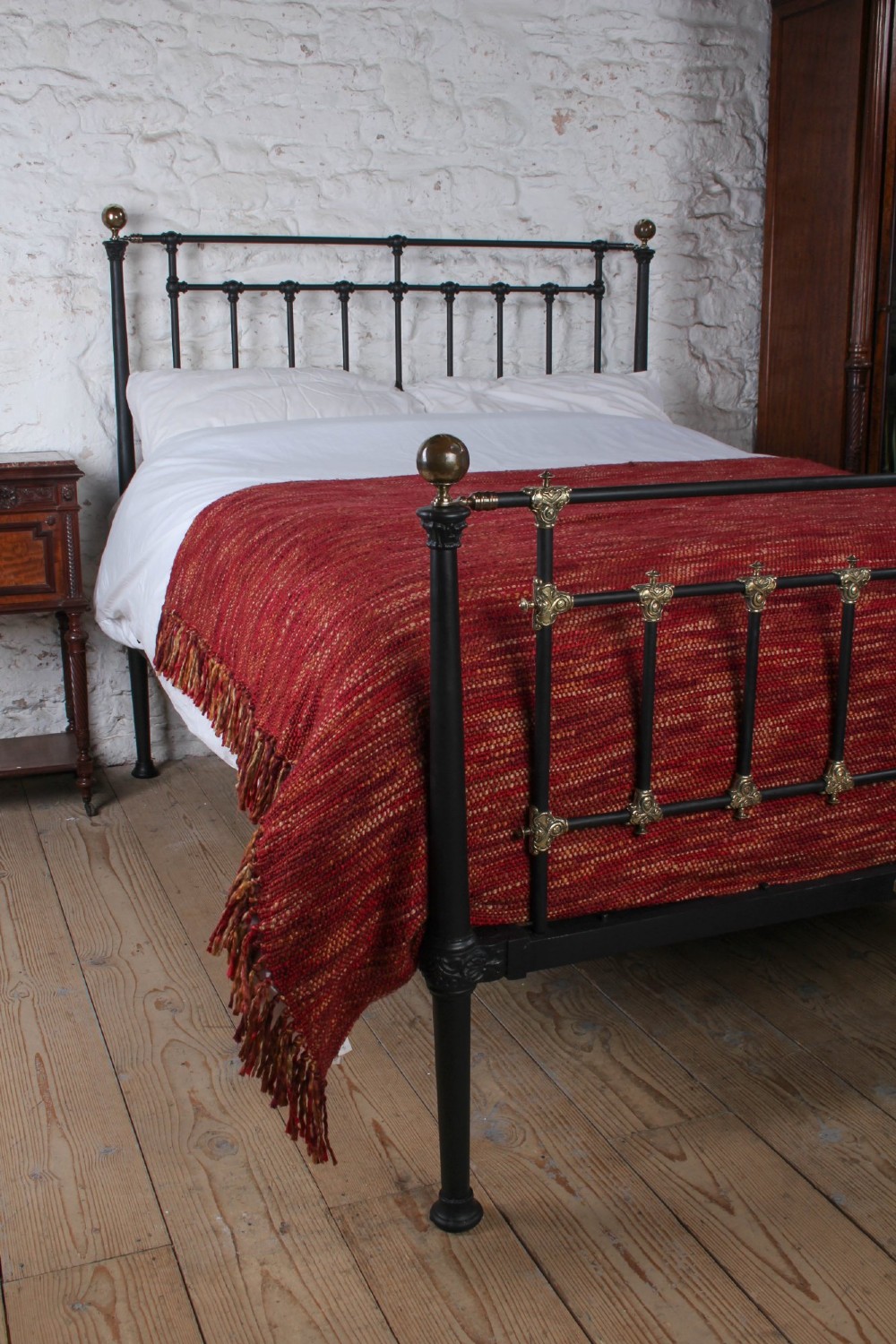 A Victorian black iron and brass king-size bedstead featuring vertical spindles, decorative brass mounts, and brass ball finials. View II