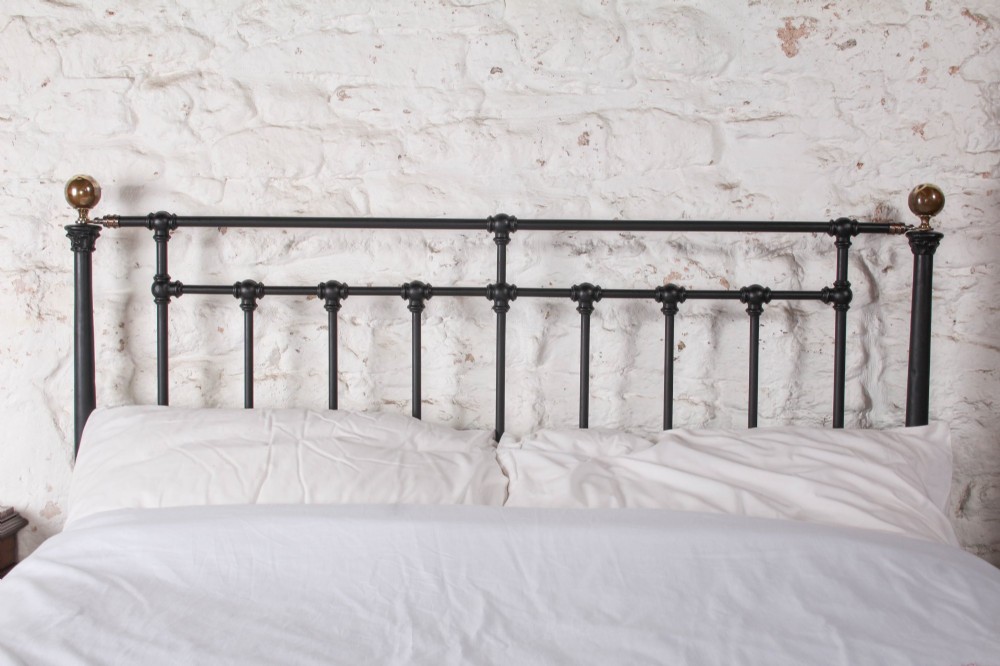 A Victorian black iron and brass king-size bedstead featuring vertical spindles, decorative brass mounts, and brass ball finials. View III