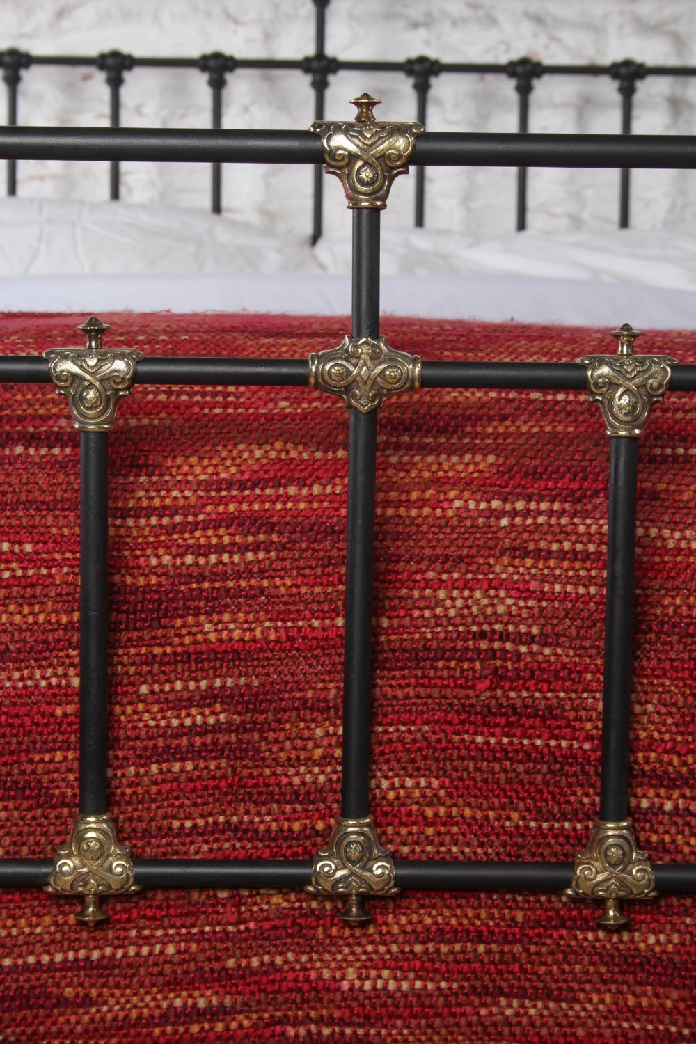A Victorian black iron and brass king-size bedstead featuring vertical spindles, decorative brass mounts, and brass ball finials. View V