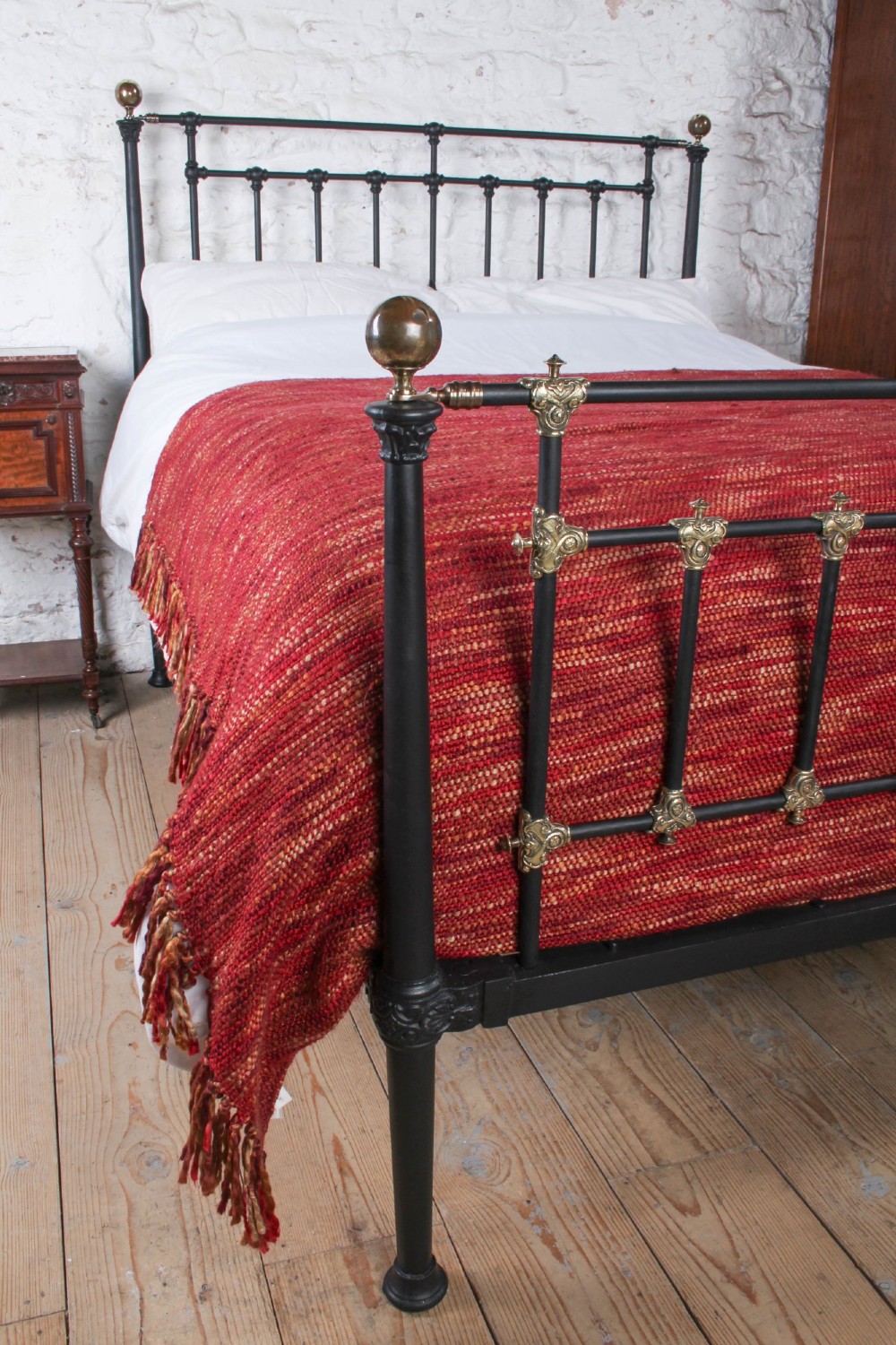 A Victorian black iron and brass king-size bedstead featuring vertical spindles, decorative brass mounts, and brass ball finials. View IX